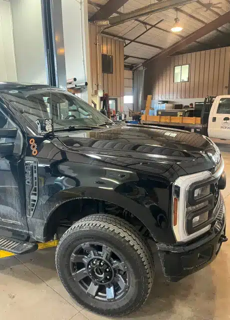 Powerstroke diesel repair in in Carbondale, CO by JW Diesel & Automotive. An image of black Ford pick up inside an auto repair shop.