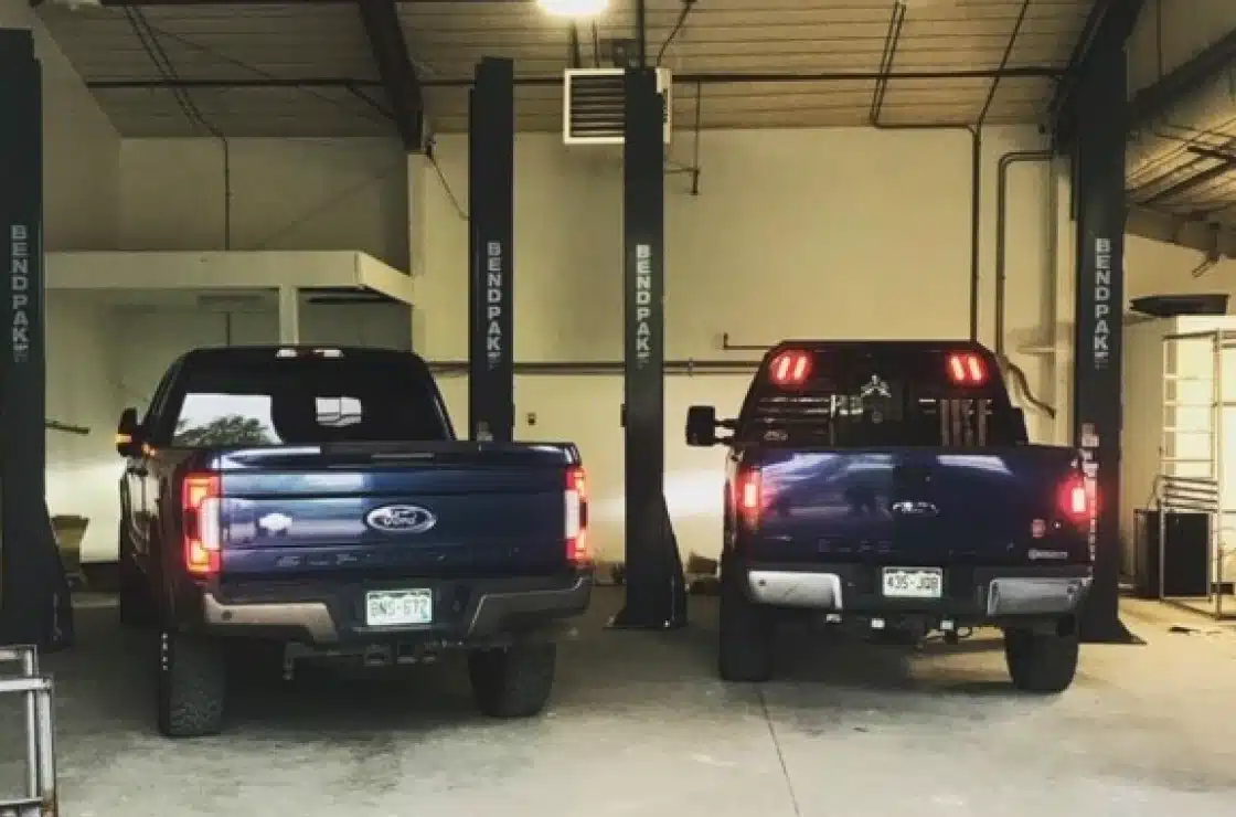 Careers in Carbondale, CO by JW Diesel & Automotive. An image of two blue trucks inside of an auto repair shop.