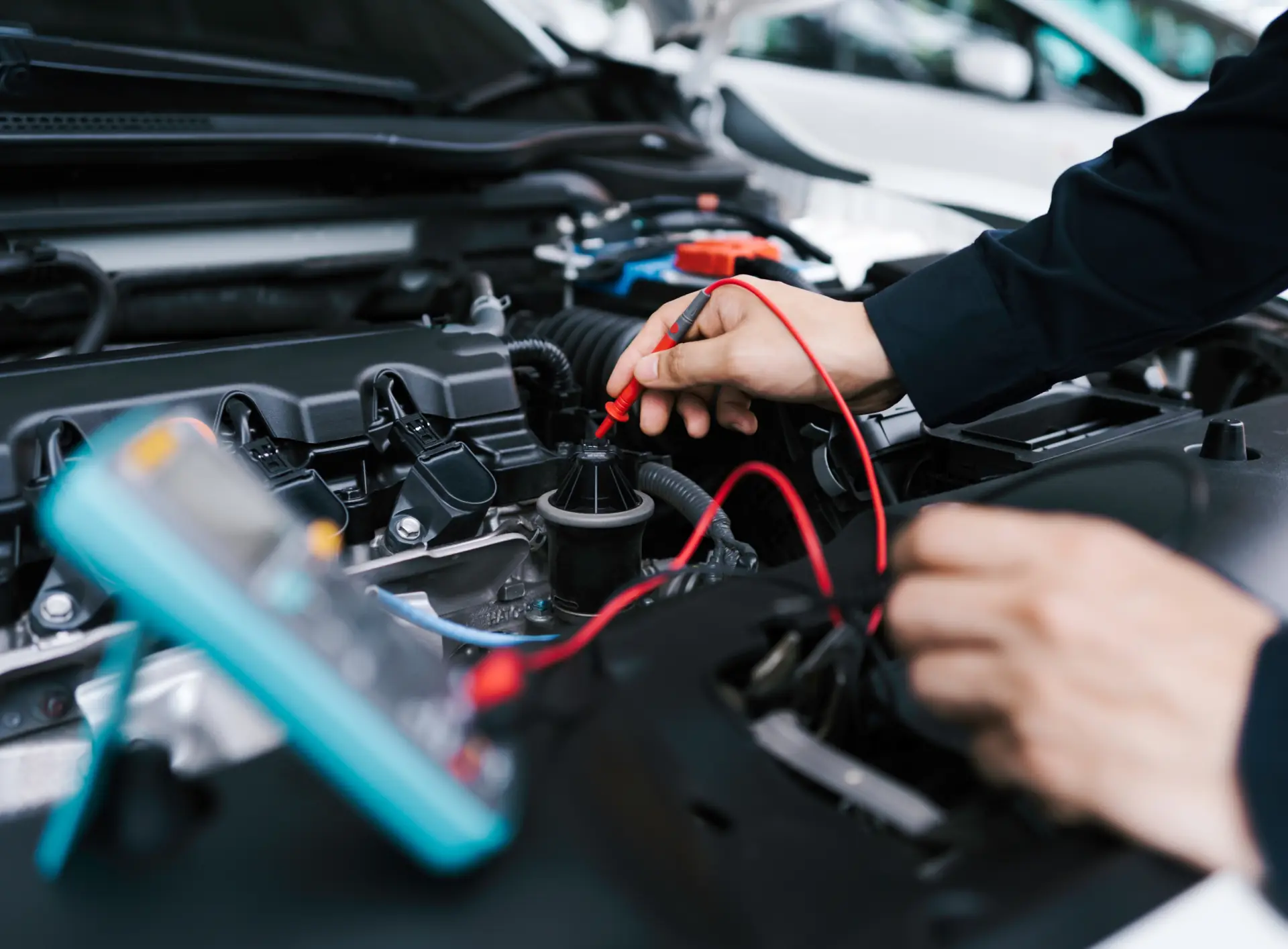Electrical Diagnostics & Repair in Carbondale, CO by JW Diesel & Automotive. A mechanic holding an auto electrical diagnostic tool and testing the vehicle's car battery while its hood is open.