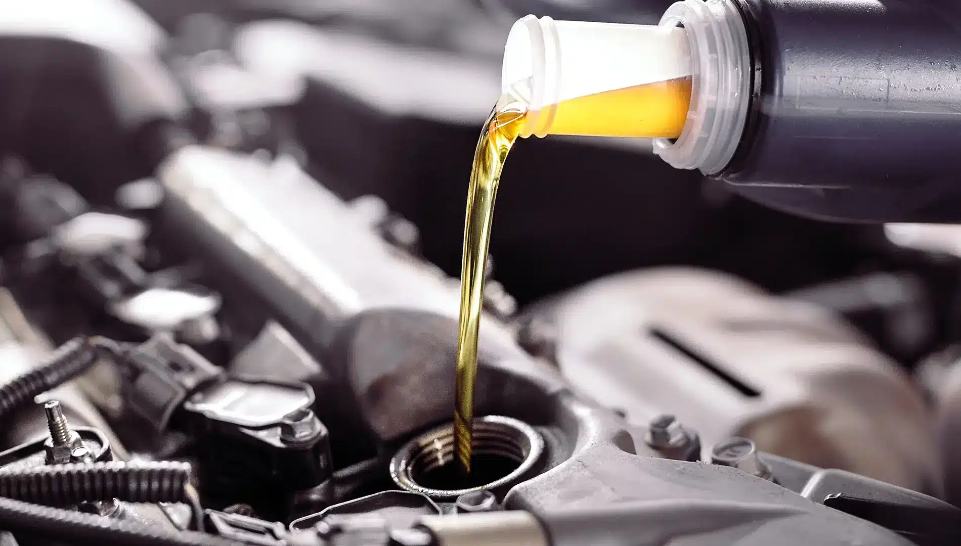BG fluid services in Carbondale, CO by JW Diesel & Automotive. A close up image of a mechanic pouring oil into a car engine.