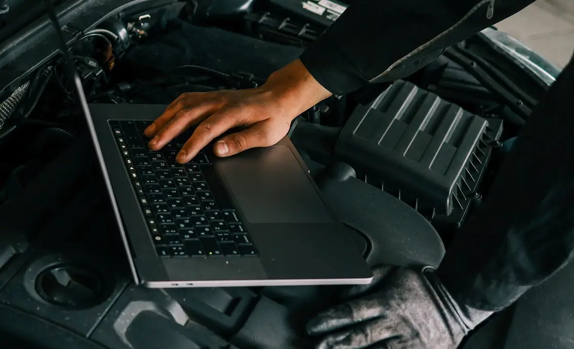 Vehicle inspections in Carbondale, CO by JW Diesel & Automotive. A mechanic using a laptop on top of a car's engine that is undergoing vehicle inspection.