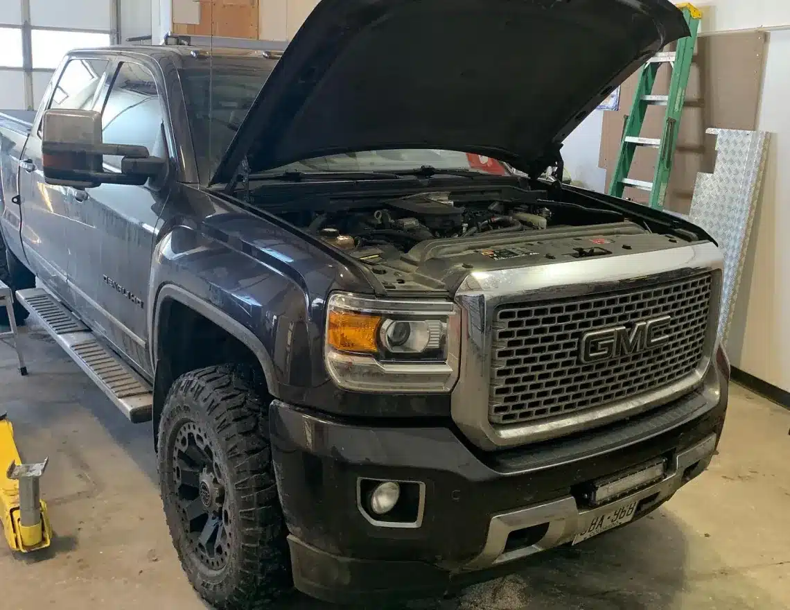 Auto repair services in Carbondale, CO by JW Diesel & Automotive. An image of A black GM truck with its hood open inside an auto repair shop.