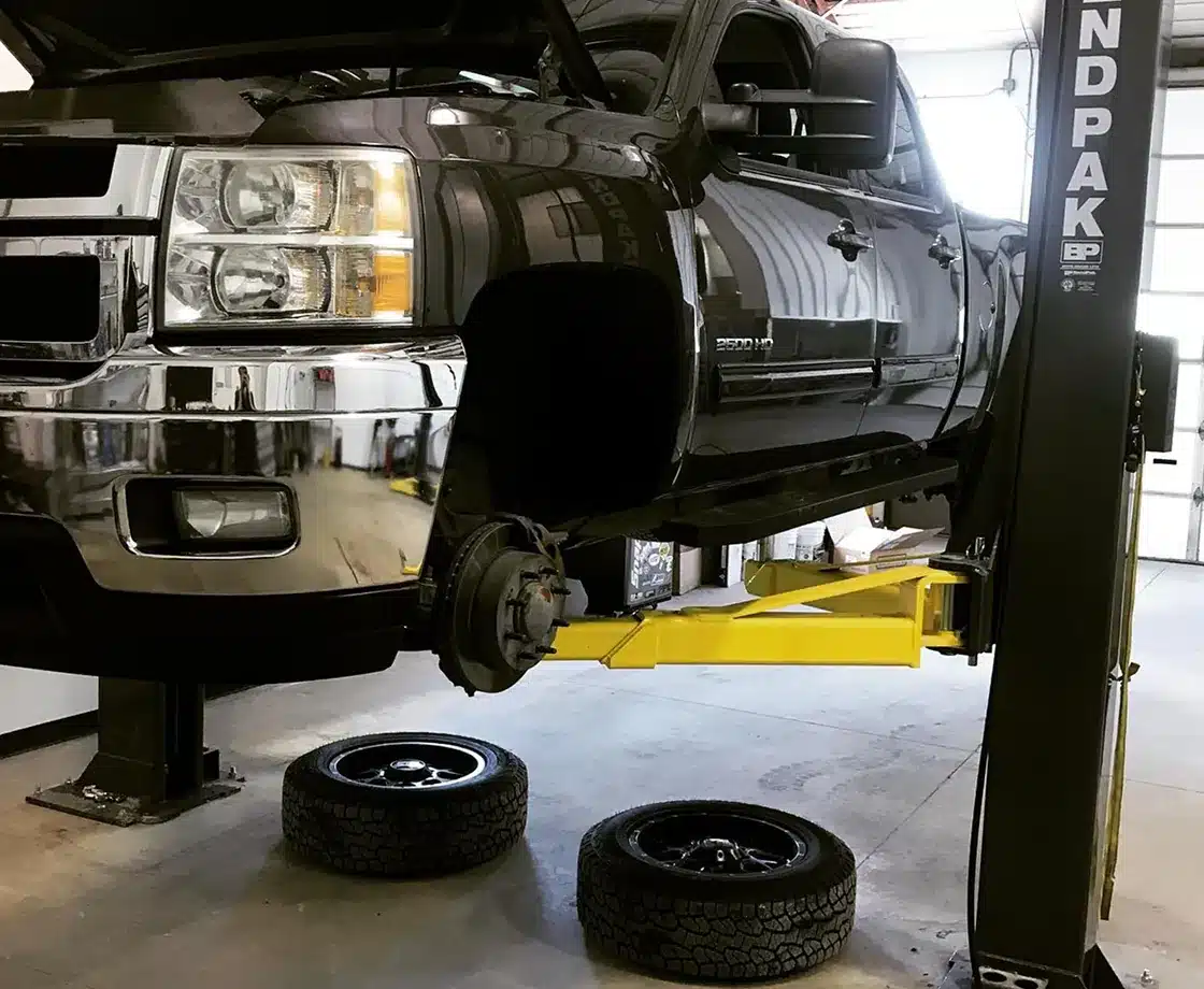 a black truck on a lift in a garage